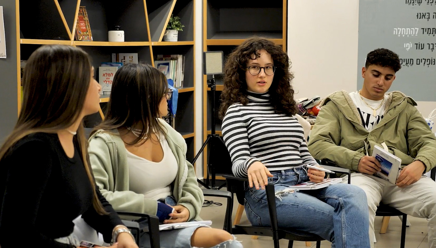 Group of four teenagers sitting on chairs and engaging in a discussion.