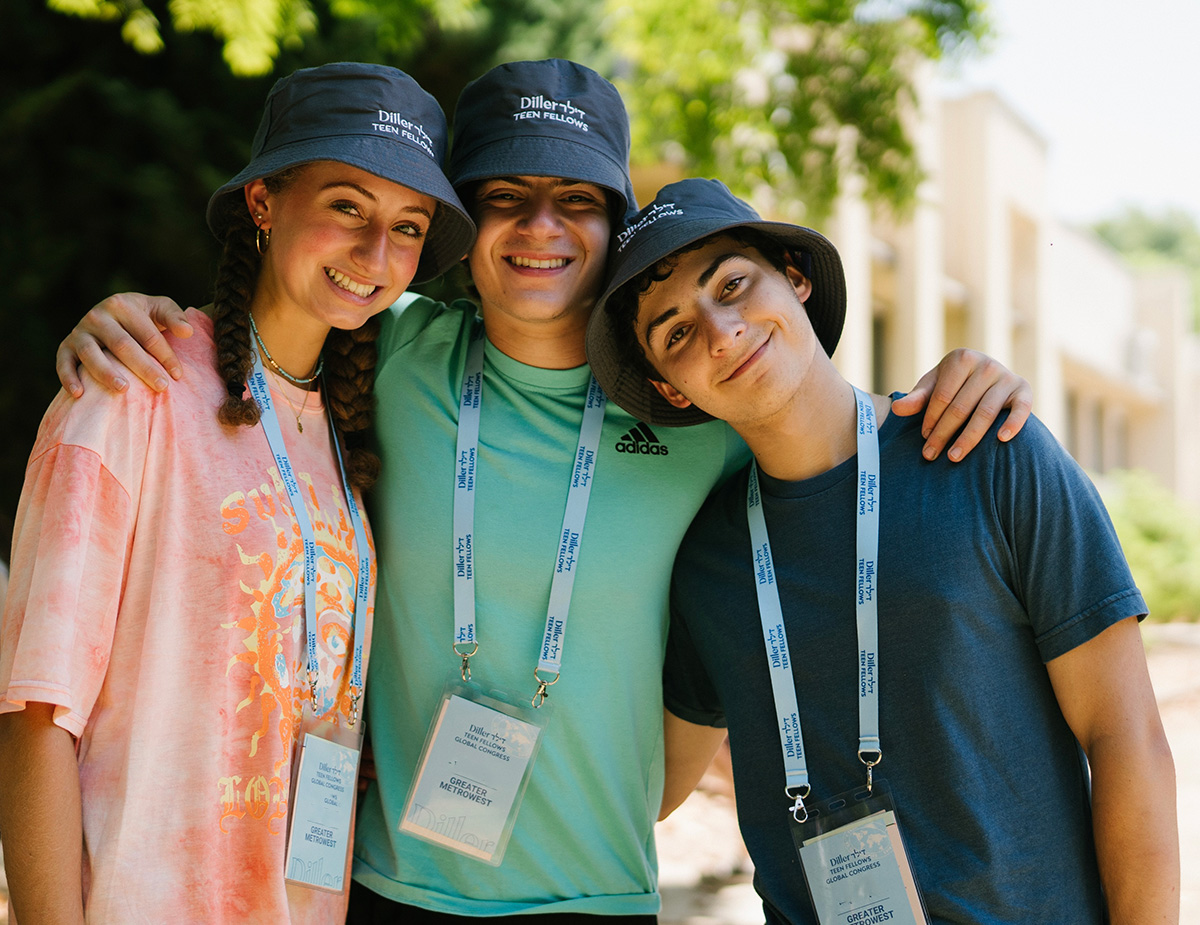שלושה עמיתים עם כובעים כחולים תואמים מחייכים למצלמה עם זרועותיהם אחד סביב השני.